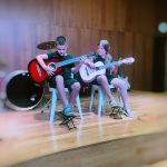 Two beginner students performing classical guitar on the wooden stage at La Violeta in Gracia, Barcelona, at a Shine Music School beginners concert
